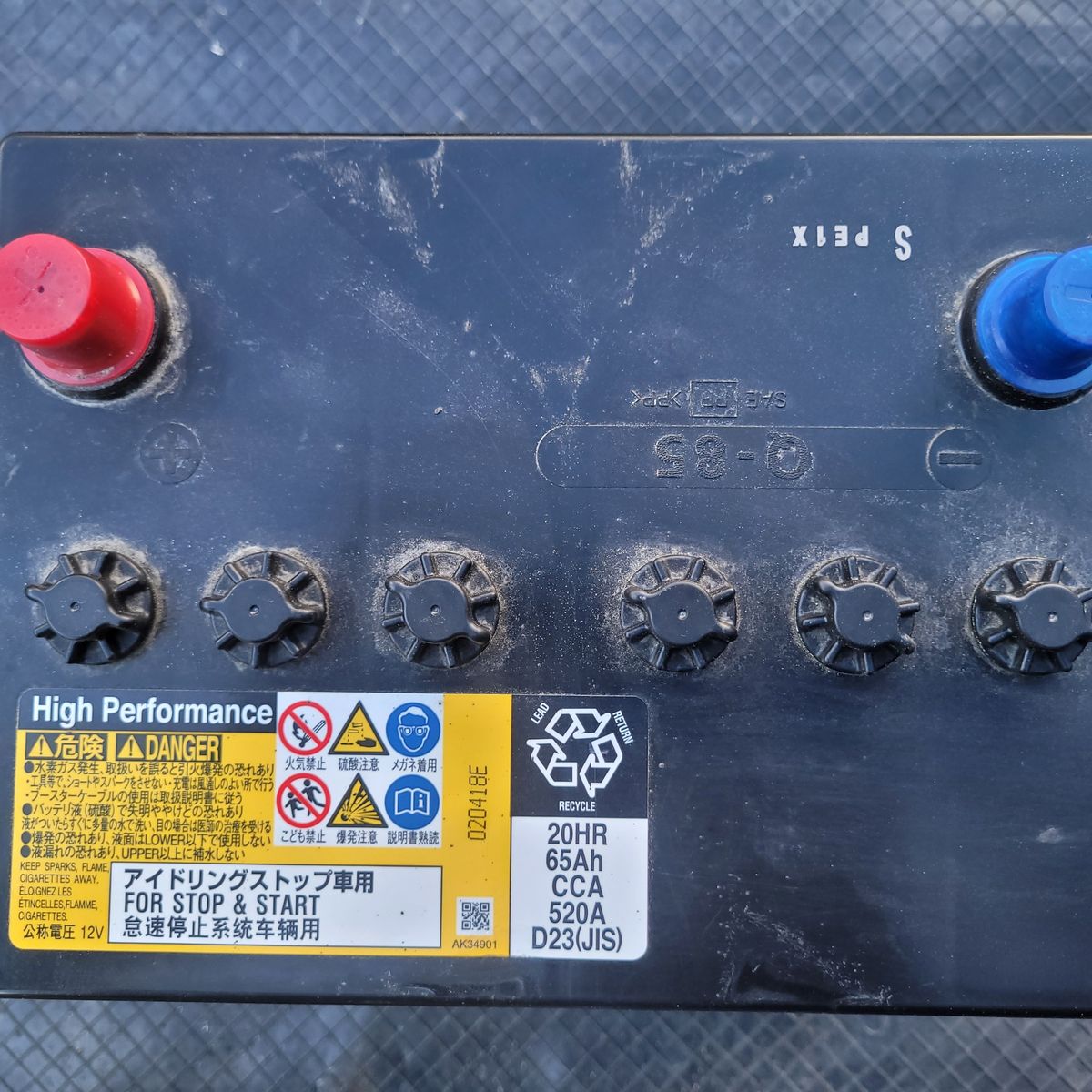 Car Stop-Start System Battery with Warning Labels Close-up of automotive stop-start battery terminals and safety labels