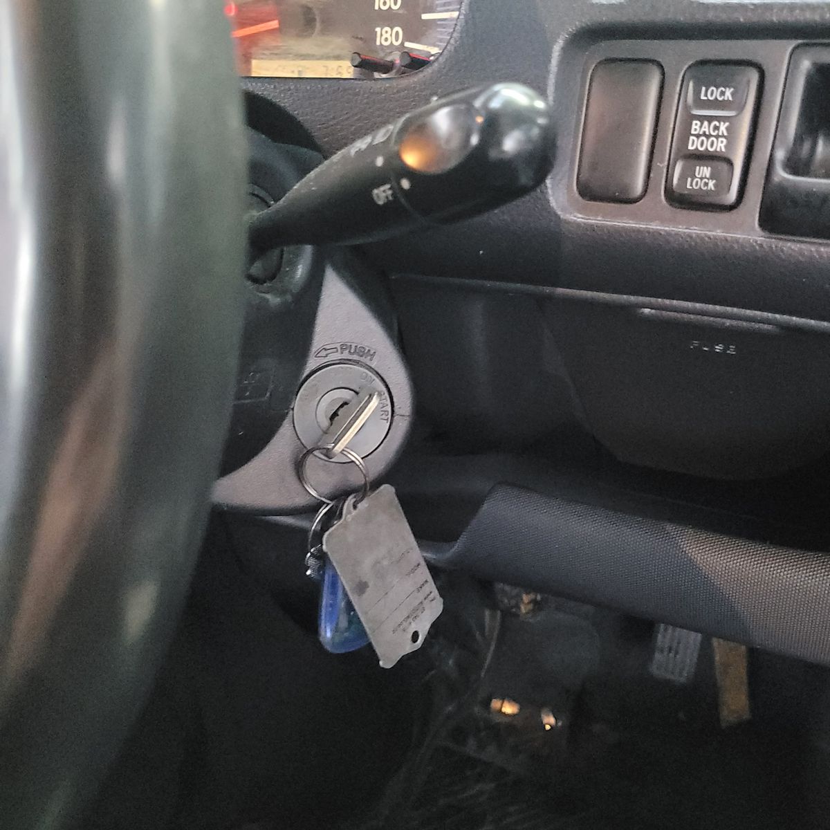 Car Ignition with Keys Inserted Close-up of car ignition with keys in the slot and dashboard controls visible.