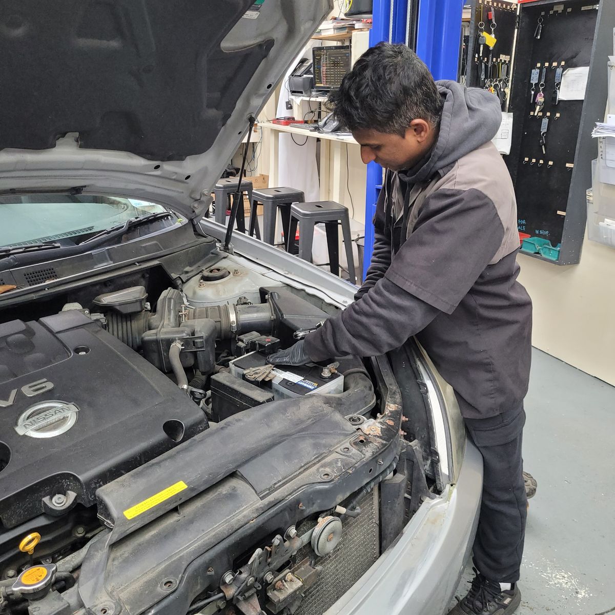Auto Mechanic Repairing Car Engine Mechanic working under car hood in a repair shop