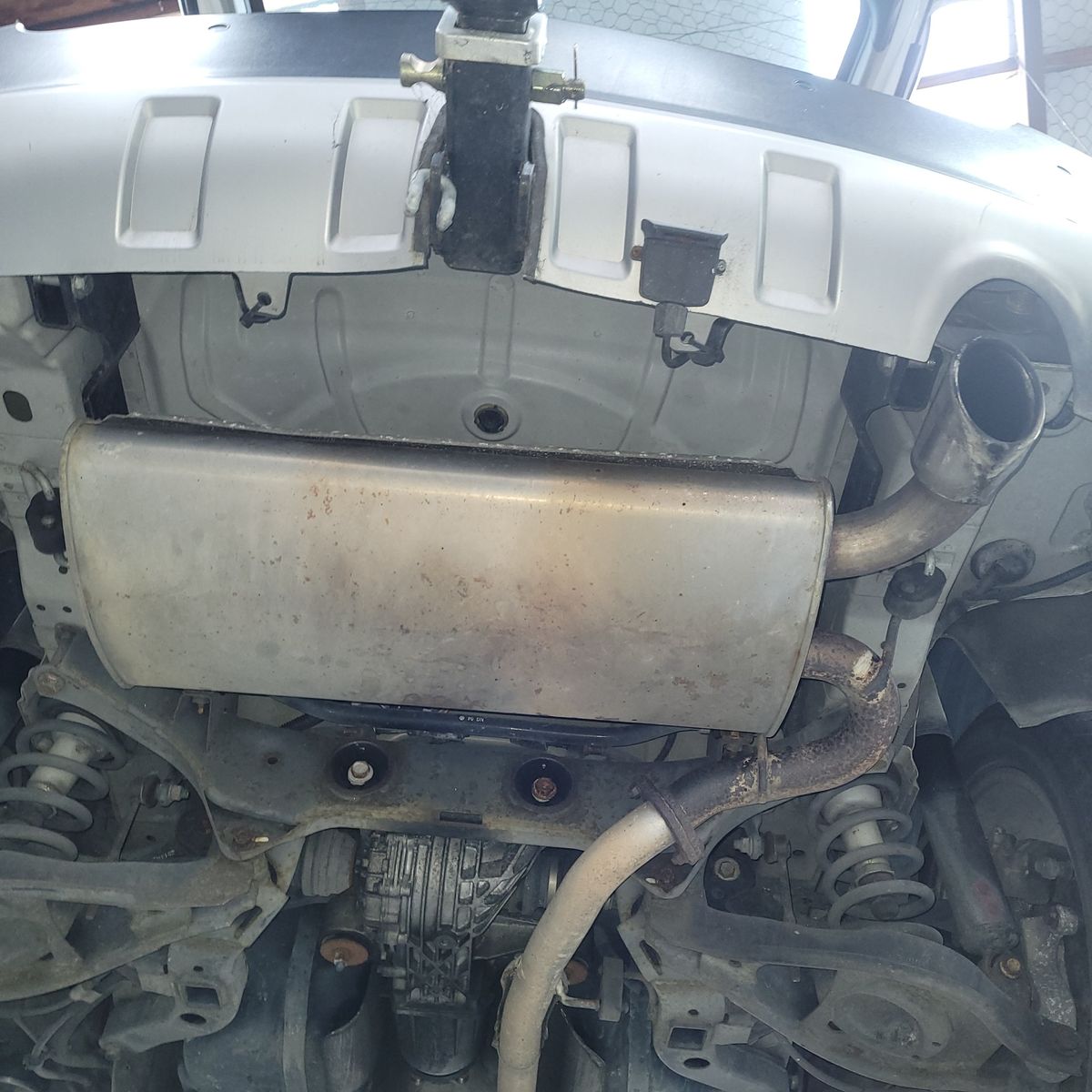 Car muffler and exhaust pipe seen from beneath the vehicle