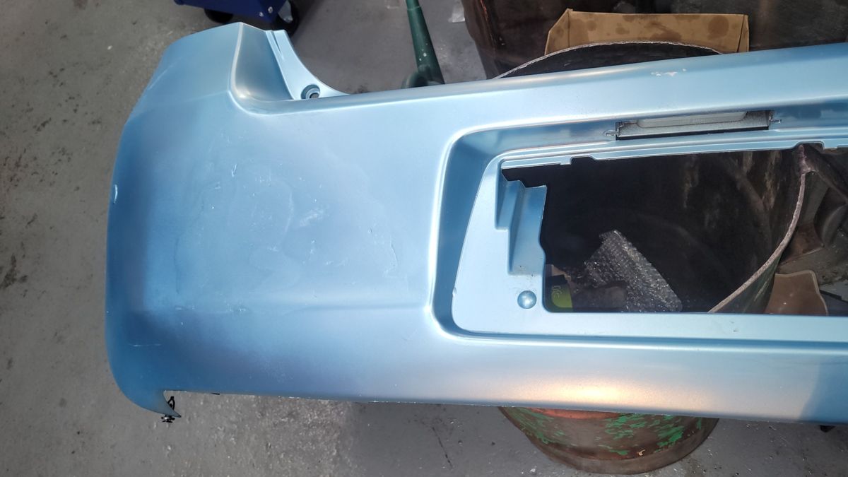 Light blue car bumper showing uneven paint and surface imperfections.