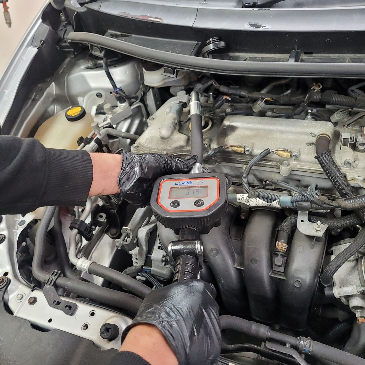 Mechanic in gloves using pressure gauge on car engine during premium service