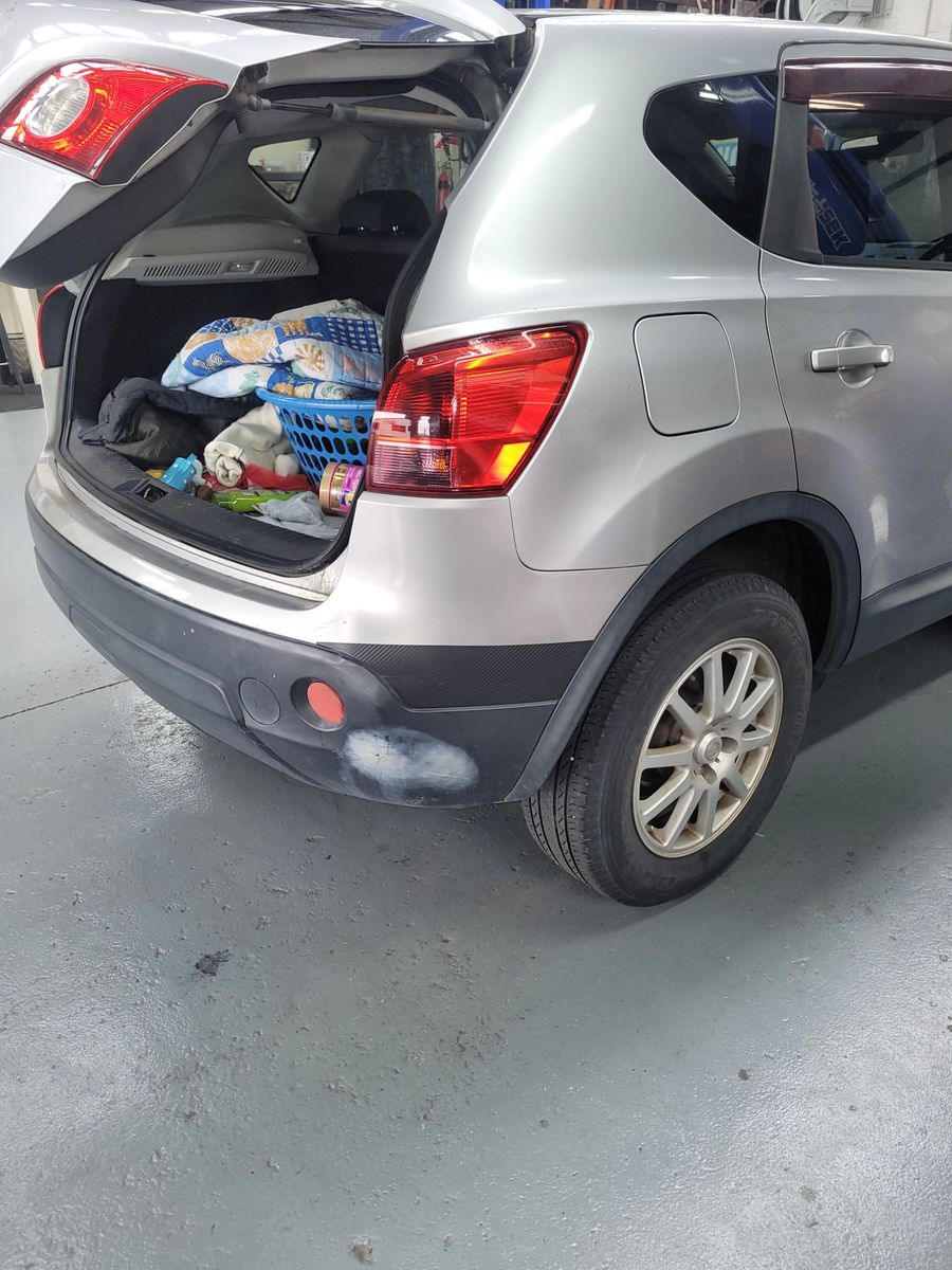 SUV rear trunk open in garage with belongings inside Open SUV trunk showing blankets, laundry basket, and toys inside