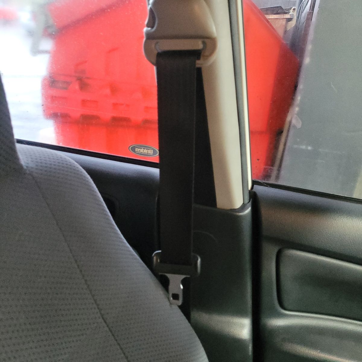 Close-up of a seatbelt next to a car seat and window