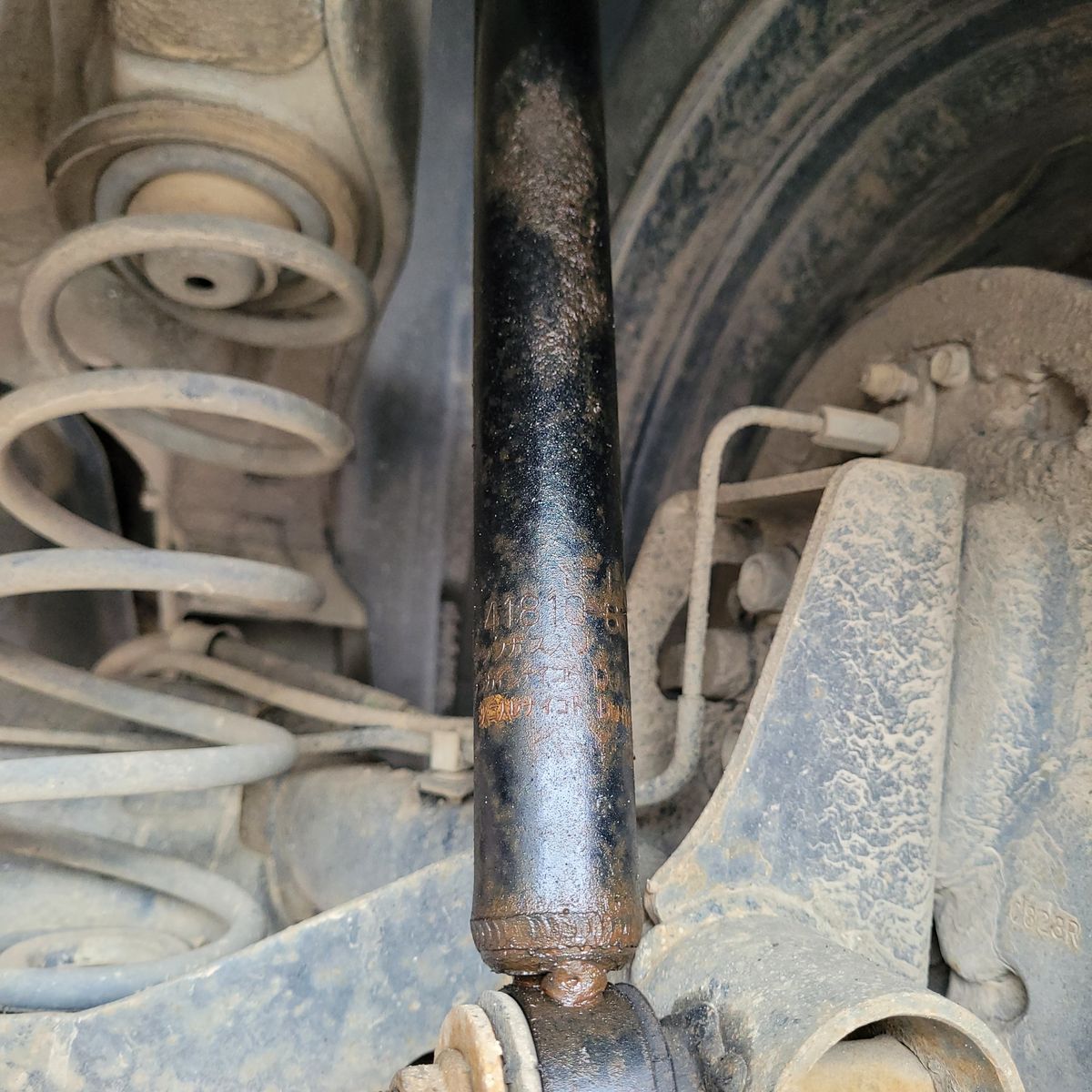 Close-up View of a Car Shock Absorber Dusty shock absorber and suspension spring on a vehicle wheel assembly