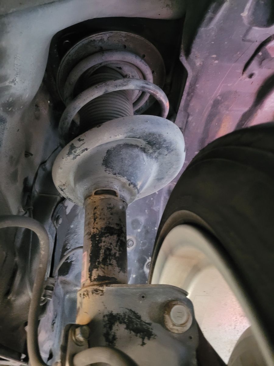 Close-up of Car Shock Absorber and Spring Rusty shock absorber and coil spring under a vehicle near the wheel