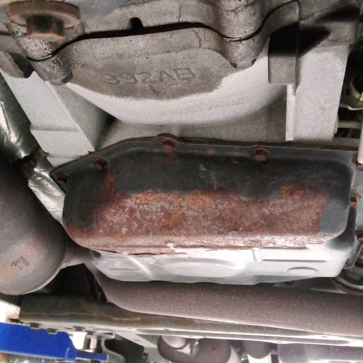 View of a car’s undercarriage showing a rusted power steering system component.