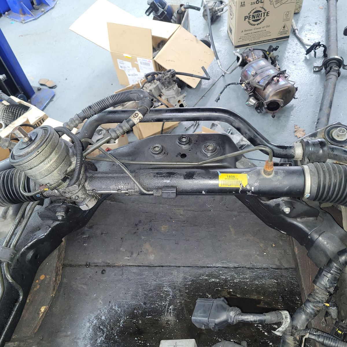 Car Steering Rack with Attached Components Close-up of a steering rack assembly mounted on a subframe in a workshop