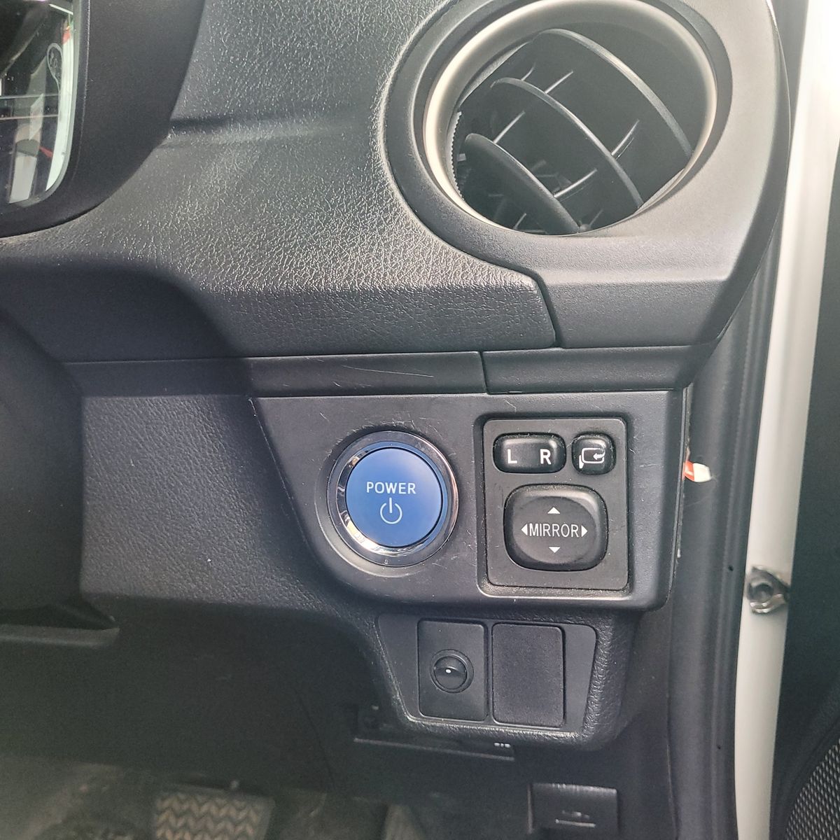 Car Start/Stop Power Button and Mirror Controls Close-up of a car's blue power start/stop button and mirror adjust controls