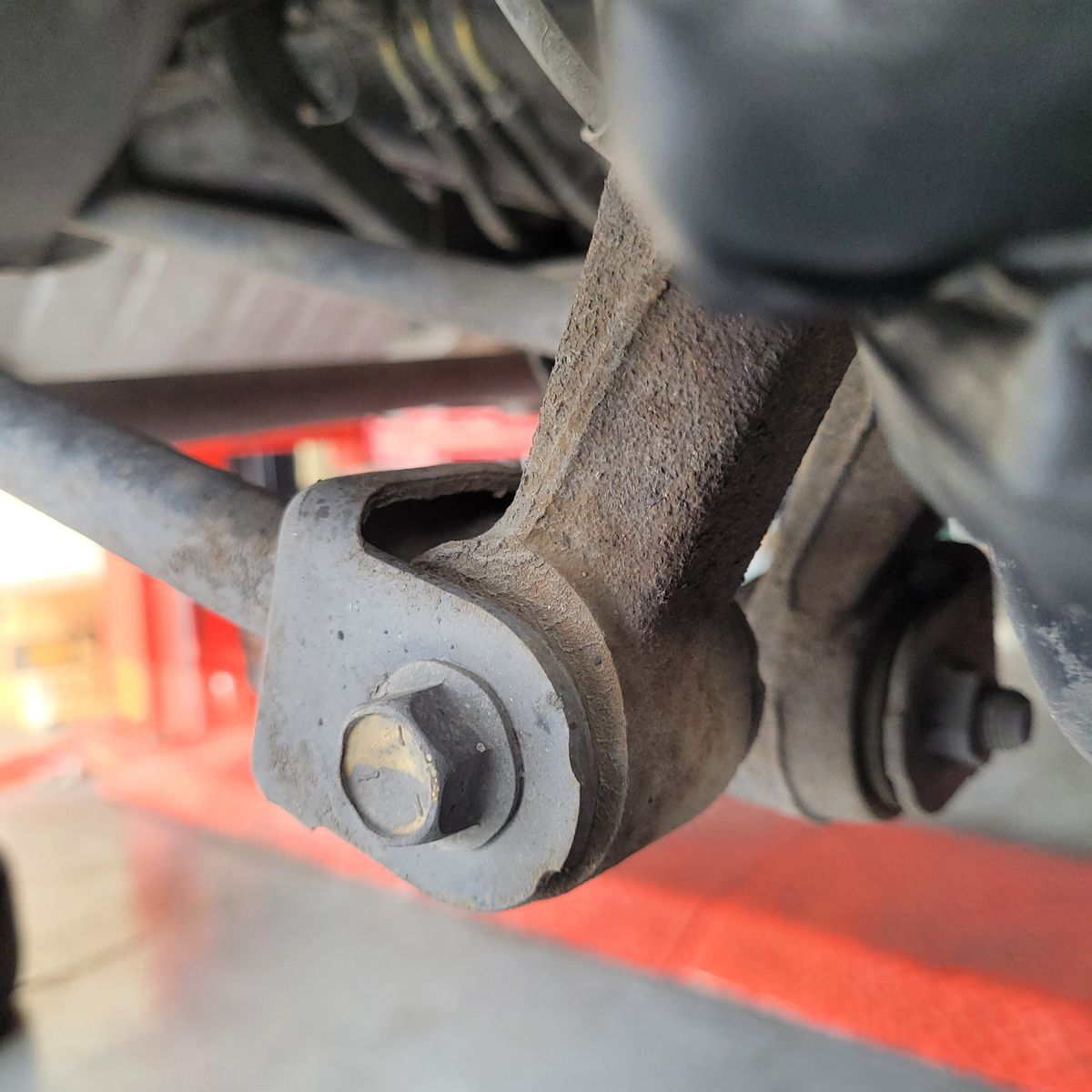 Detail view of a car suspension bush and bolt under a vehicle