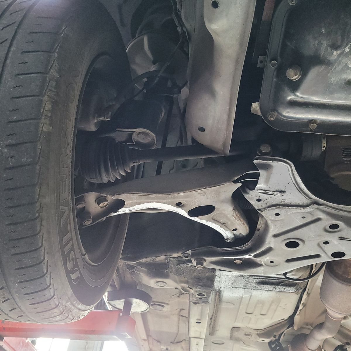 View of a car's suspension, control arm, and wheel from underneath