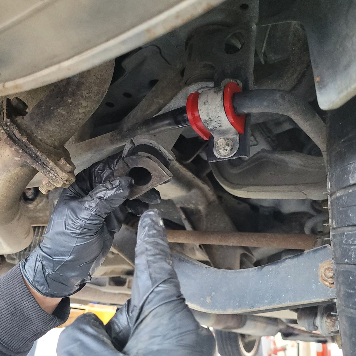 Replacing Car Sway Bar Bushings Mechanic installing new sway bar bushing under vehicle