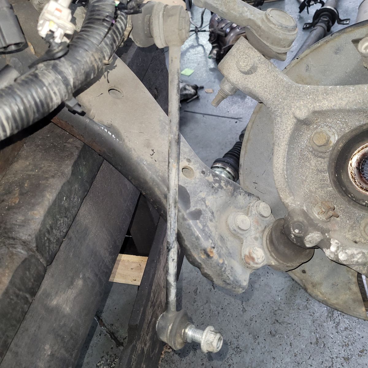 Close-Up of Vehicle Sway Bar Link and Suspension A worn sway bar link attached to a vehicle suspension assembly.