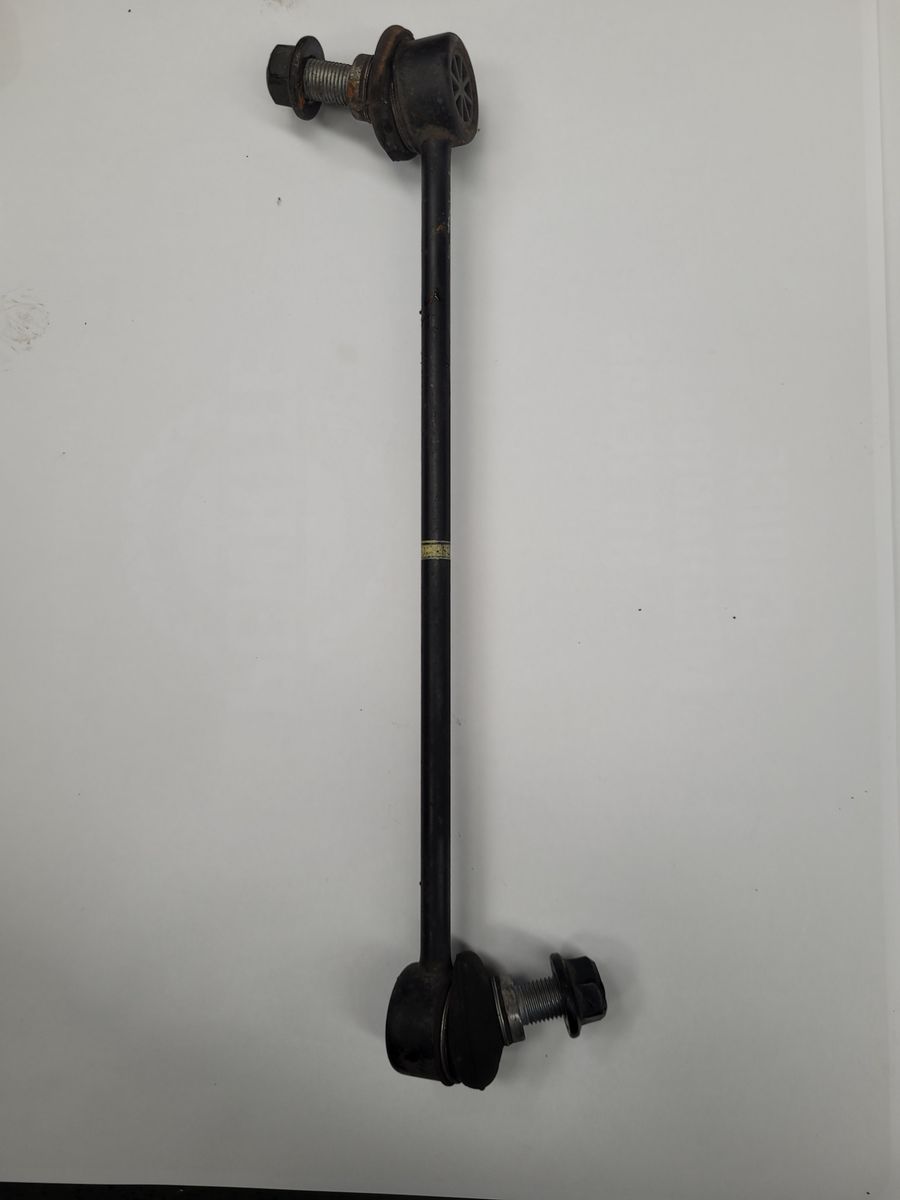 A single sway bar link with bolts, used in vehicle suspension systems, lies on a white surface.