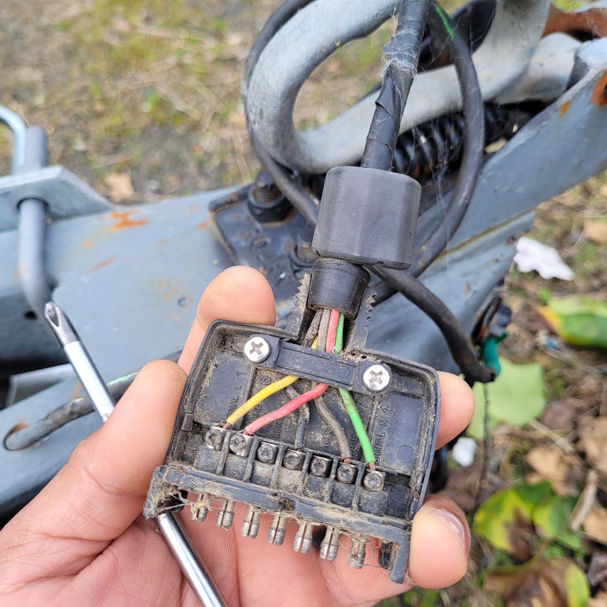Close-up of a hand holding an open tow bar wiring plug showing colored wires.