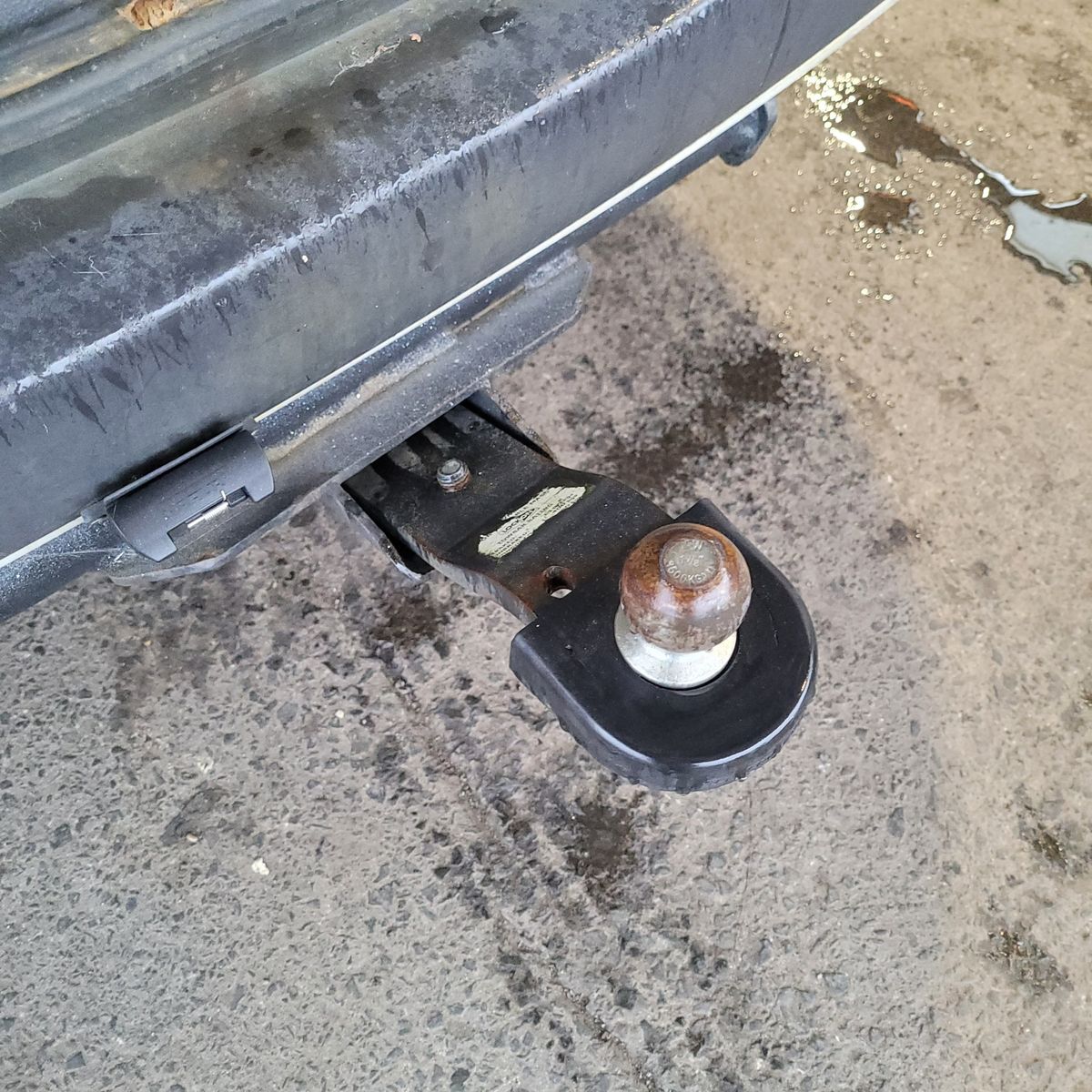 Rusty Towbar Attached to Vehicle Bumper Close-up of a car towbar with a slightly rusty tow ball on a concrete surface