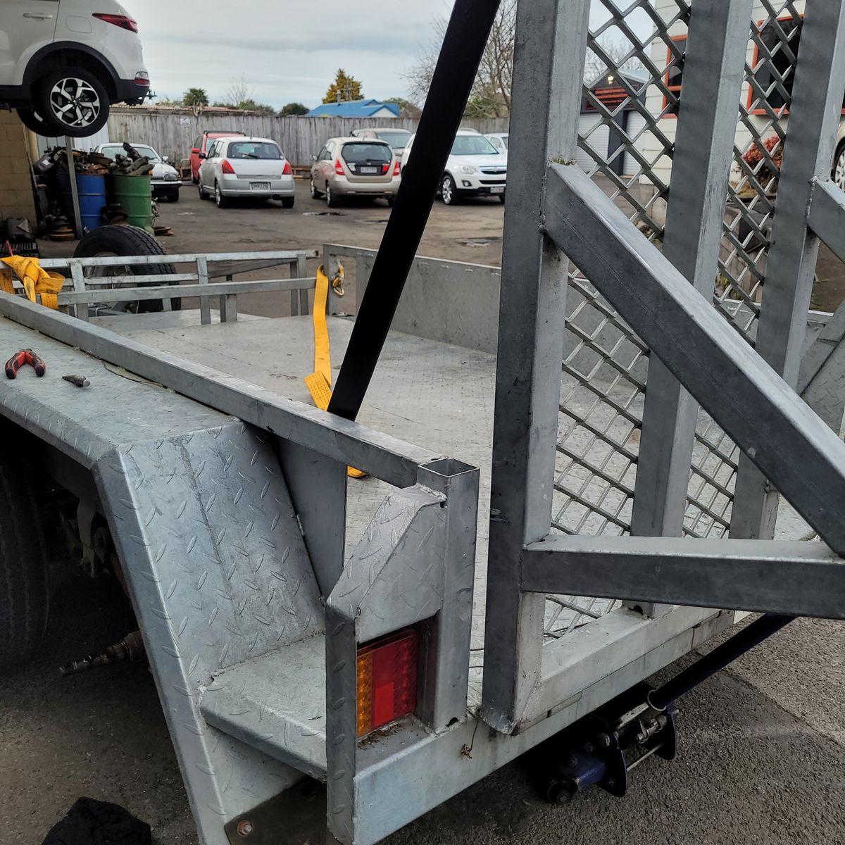 Trailer Ramp Repair in Auto Shop Yard Metal trailer with ramp undergoing repair in a busy workshop lot