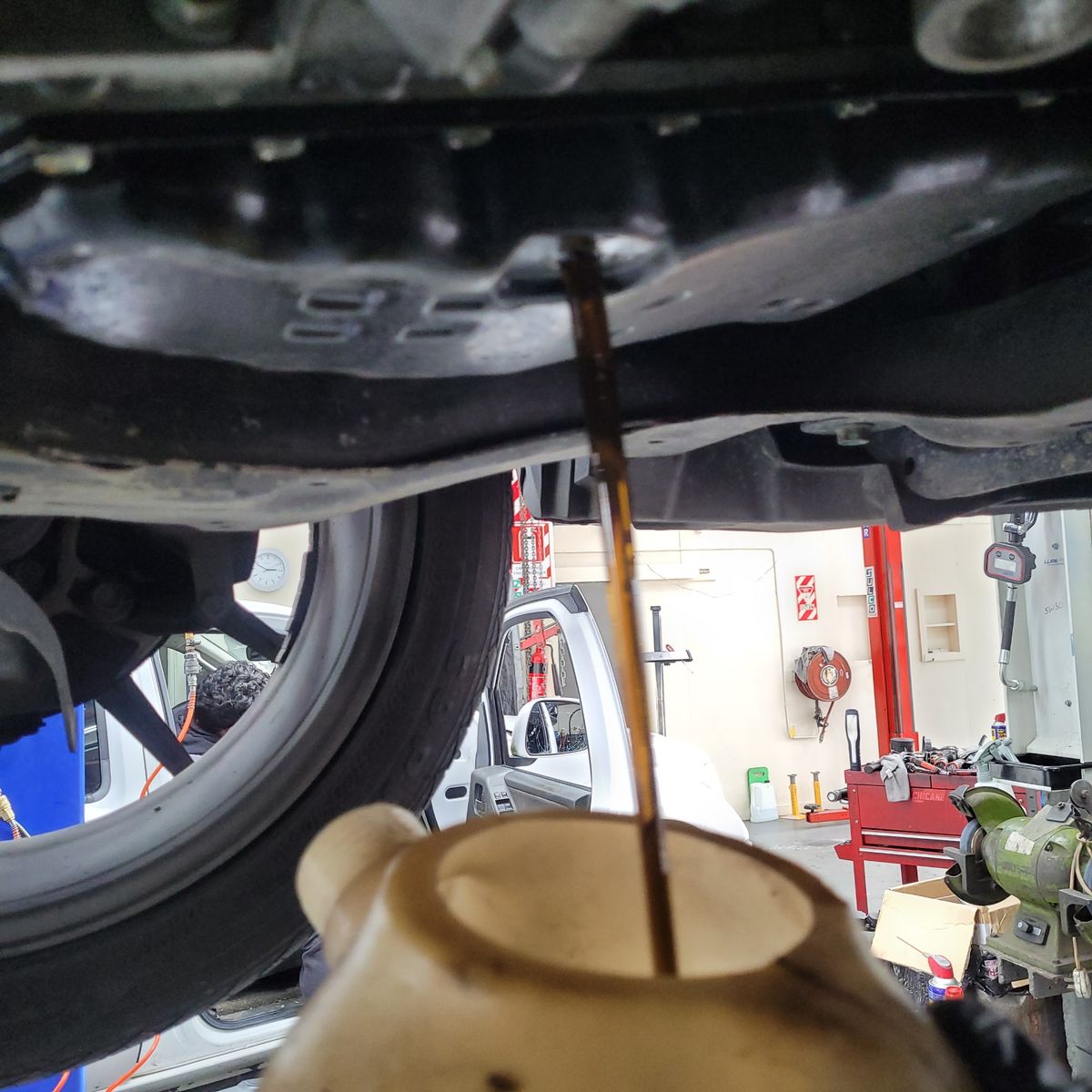 Transmission Fluid Drain in Auto Repair Shop Transmission fluid draining from a car into a container in a garage