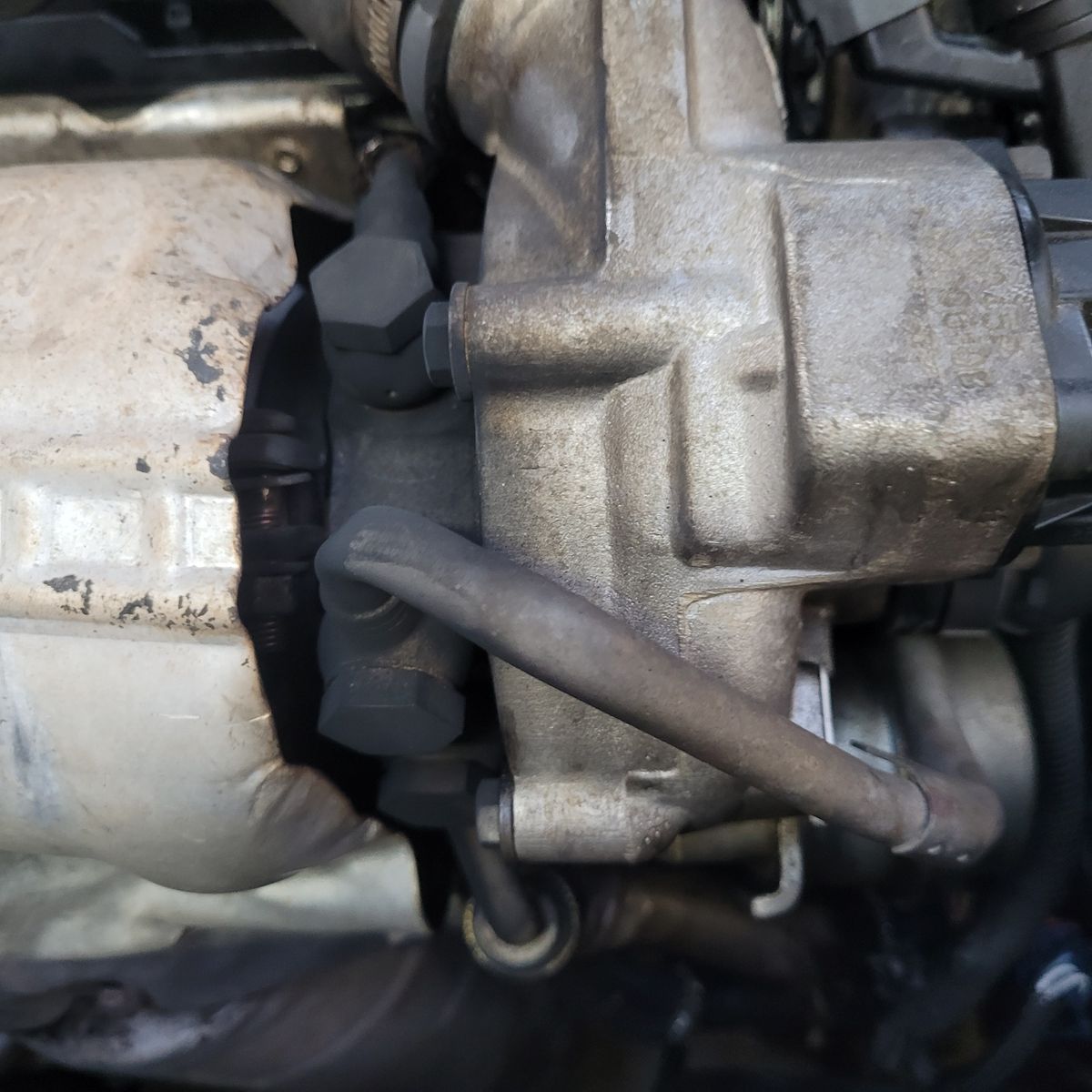 Turbocharger assembly with visible metallic housing and hoses attached