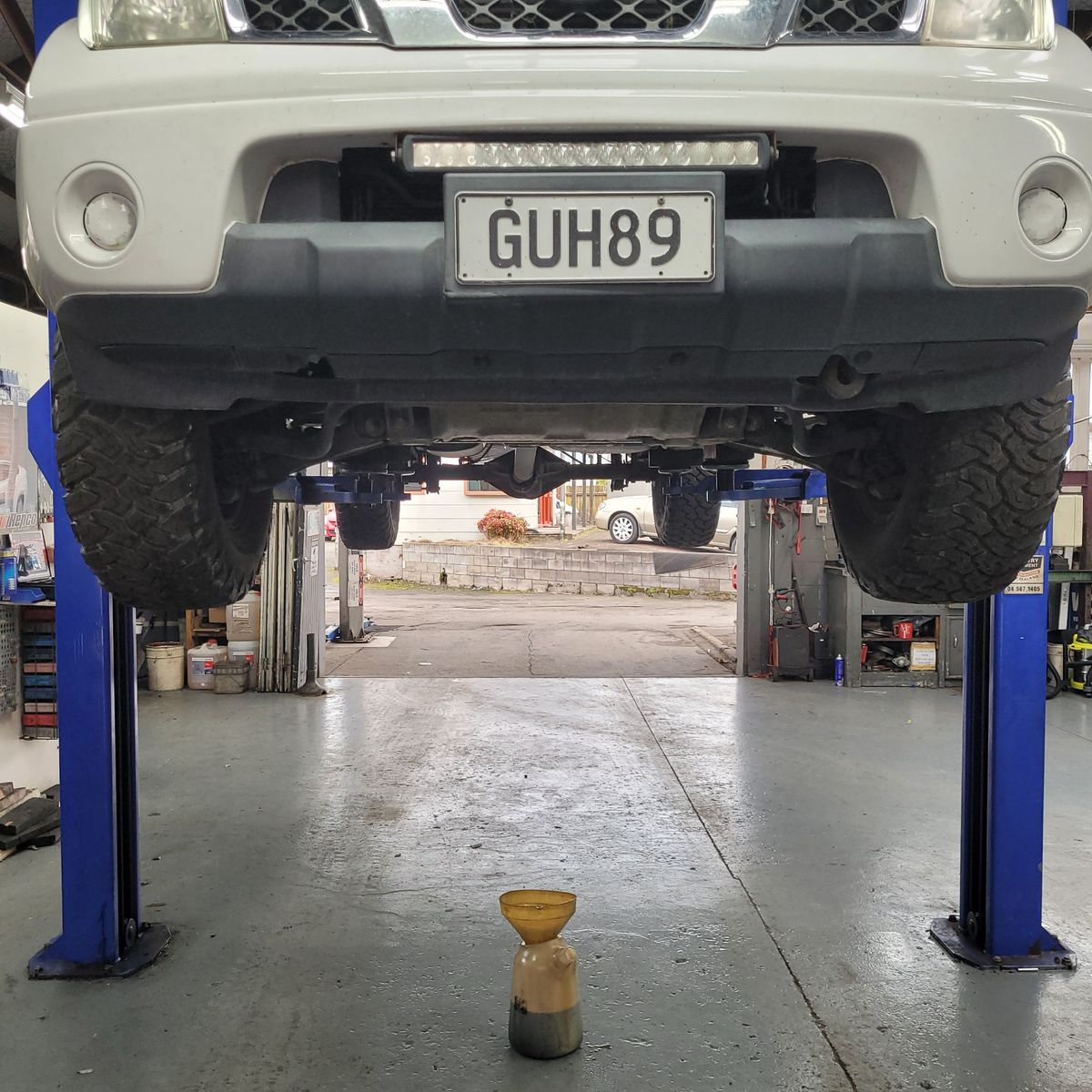 SUV raised on hydraulic lift in workshop, tyre alignment in progress