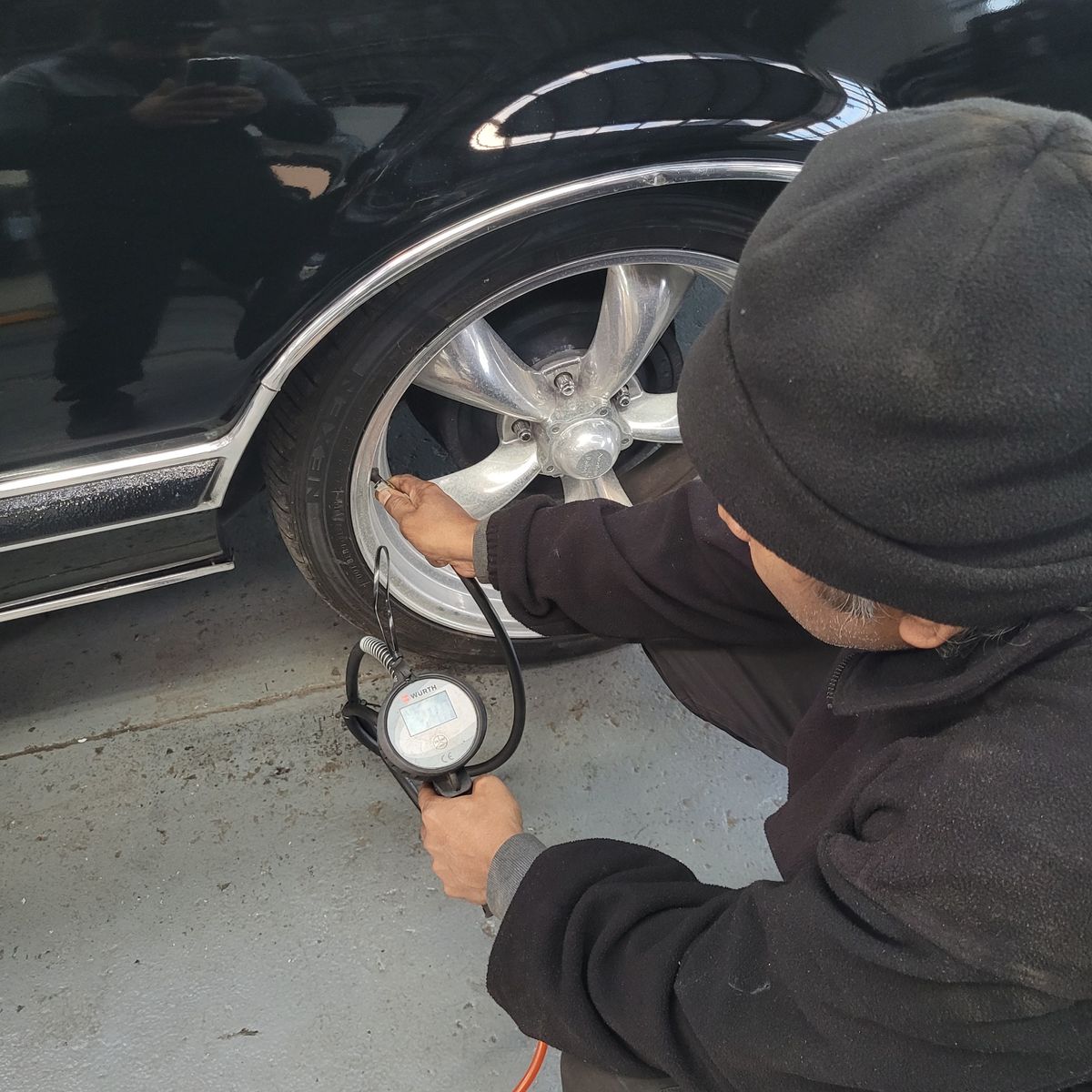 Mechanic Checking Car Tire Pressure with Gauge Person using a tire gauge to check a car's tire pressure.