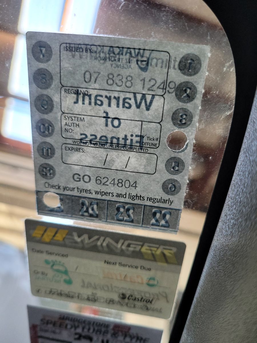 Warrant of Fitness Sticker on Car Windshield Close-up of a New Zealand Warrant of Fitness sticker and service labels on a car windshield.