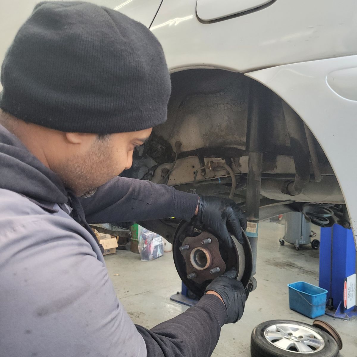 Mechanic Installs Brake Shoes on Vehicle Mechanic fitting brake shoes onto a car's wheel hub in garage